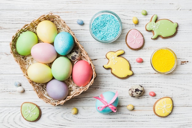 Colorful easter cookies in basket with Multi colors Easter eggs on colored background Pastel color Easter eggs holiday concept with copy space