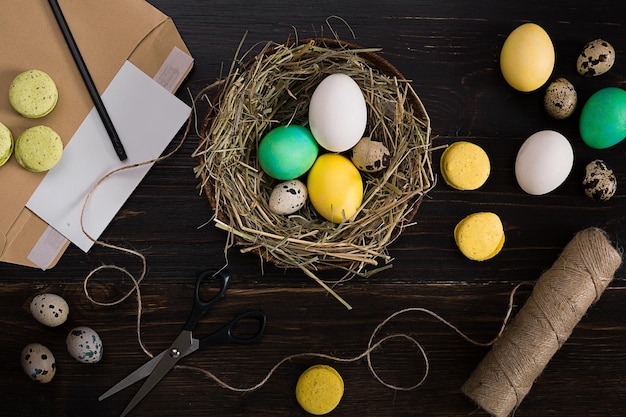 Colorful easter egg in nest on dark wood board