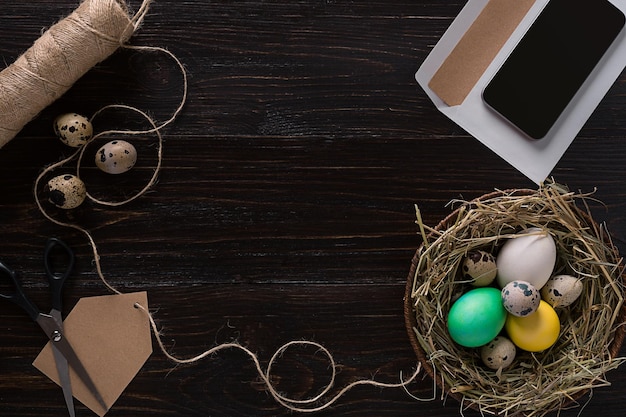 Colorful easter egg in nest on dark wood board