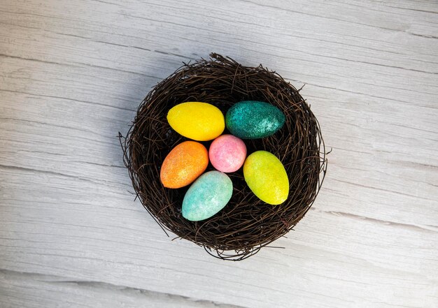 Colorful easter egg nest with extra white or gray wood board background for room or space for copy t...