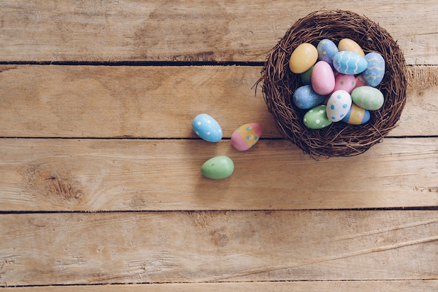 Colorful Easter egg and nest on wooden table background with copy space.