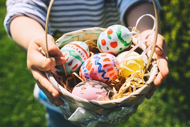 Colorful Easter eggs in basket Children gathering painted decoration eggs in spring park Kids hunt for egg outdoors Festive family traditional play game on Easter