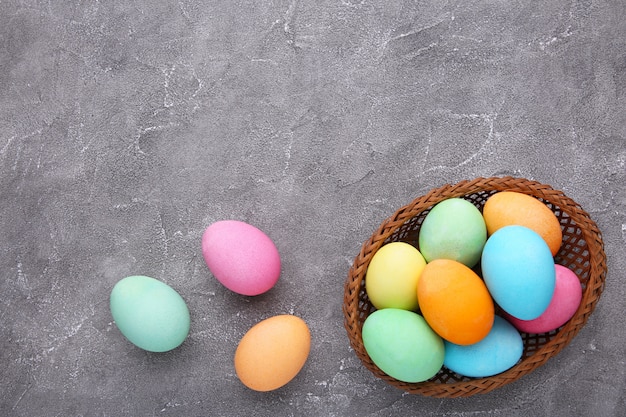 Colorful easter eggs in basket on grey cement