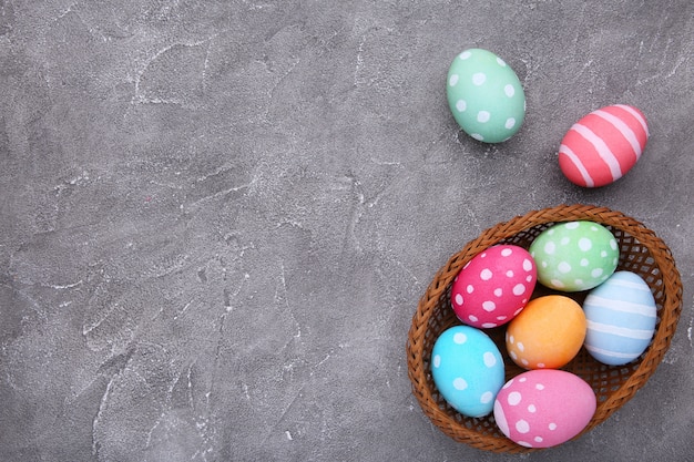 Colorful easter eggs in basket on grey cement 