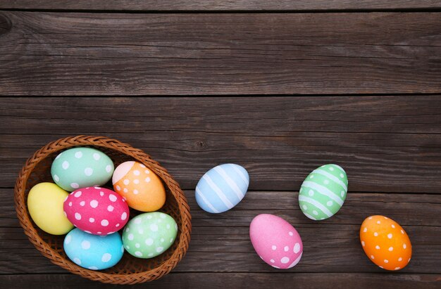 Colorful easter eggs in basket on grey wooden 