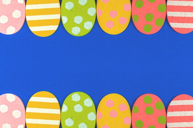 Colorful easter eggs border frame with copy space on a blue background photo