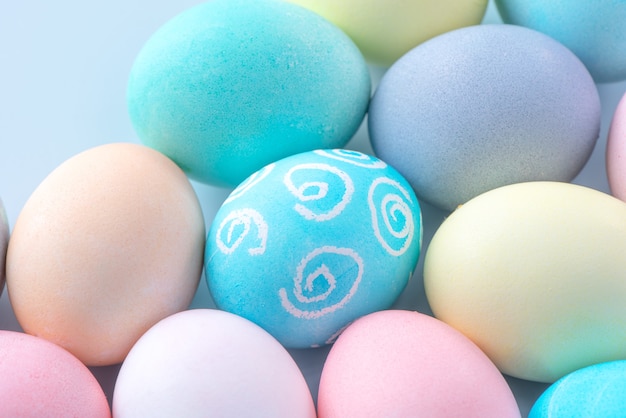 Colorful Easter eggs dyed by colored water isolated on a pale blue background, design concept of Easter holiday activity, close up, copy space.