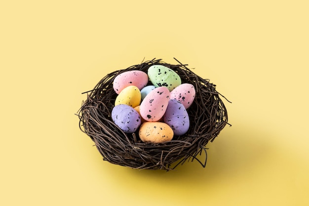 Colorful Easter eggs inside a nest on yellow background