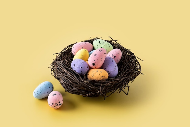 Colorful Easter eggs inside a nest on yellow background