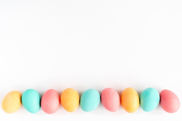 Colorful Easter eggs lined on white background Flat lay