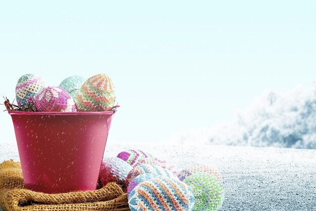 Colorful easter eggs on the nest in a red bucket with fabric on the field. Happy Easter