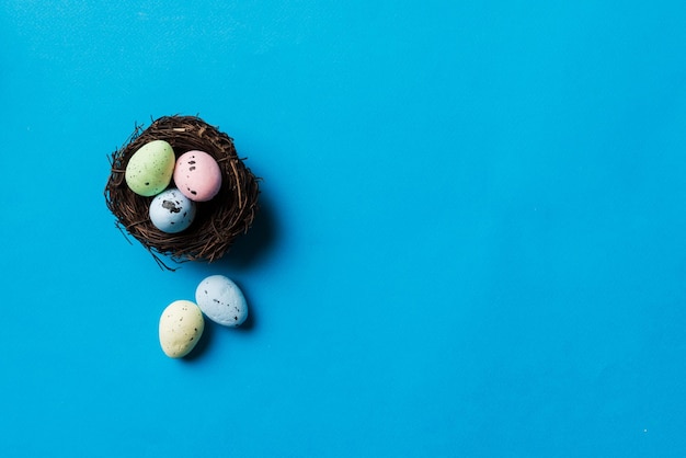 Colorful easter eggs in nest on table background with copy space top view