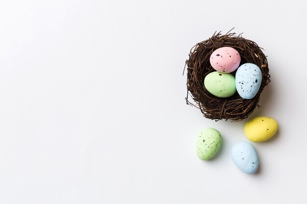 Colorful easter eggs in nest on table background with copy space top view