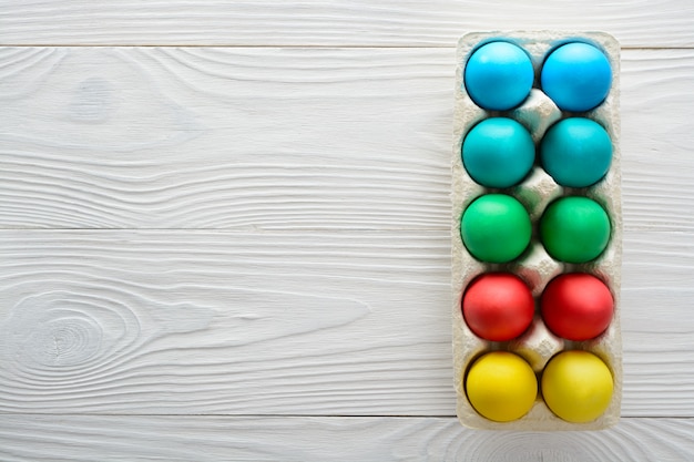 Colorful easter eggs in a tray on a white wooden table