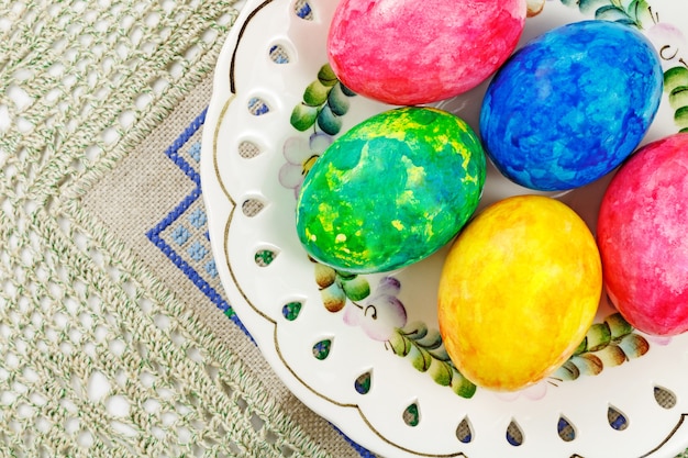 Colorful Easter eggs in white ceramic bowl on the table