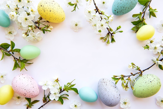 Colorful Easter eggs with spring blossom flowers isolated over white table. Colored Egg Holiday border.