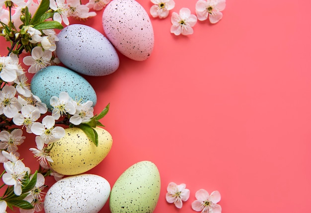 Colorful Easter eggs with spring blossom flowers over pink background.