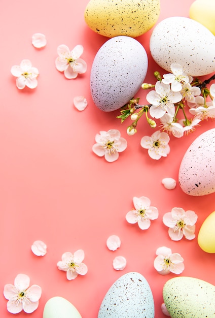 Colorful Easter eggs with spring blossom flowers over pink background.