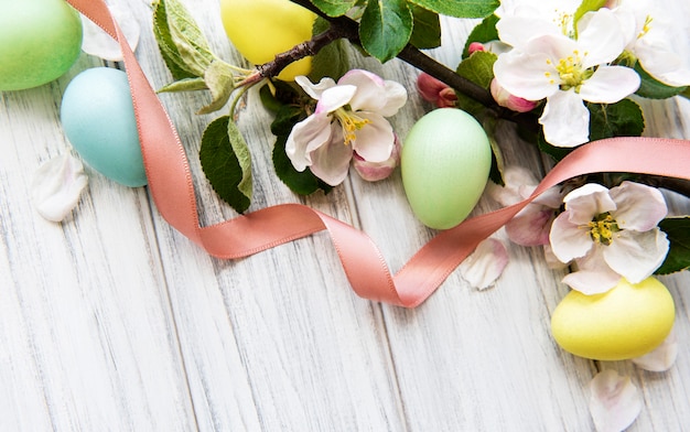 Colorful Easter eggs with spring blossom flowers over wooden background.