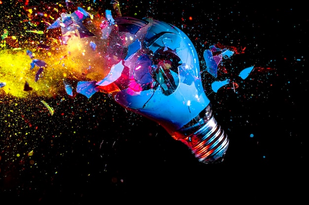 Colorful electric light bulb exploding on black