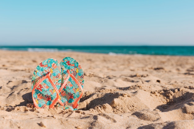 Colorful flip-flops in sand