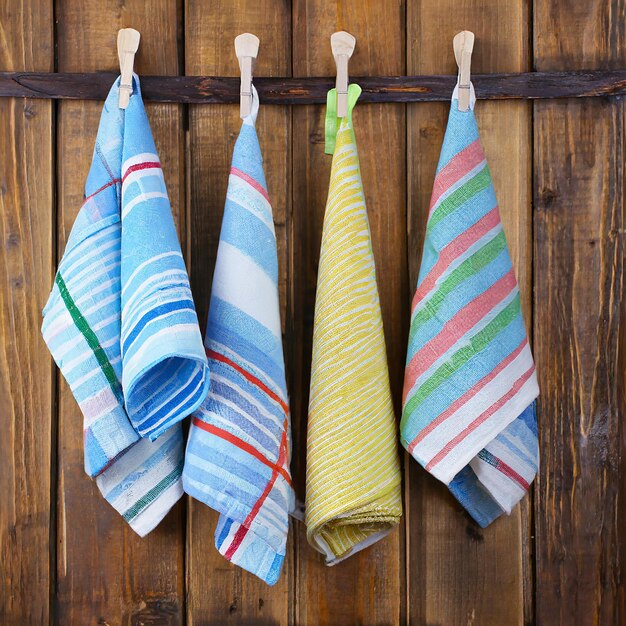 Colorful folded kitchen towels hanging on a rope on a wooden background