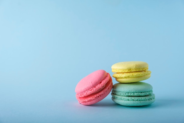 Colorful french macarons cookies macaroons on blue background Dessert vegetarian sweets close up