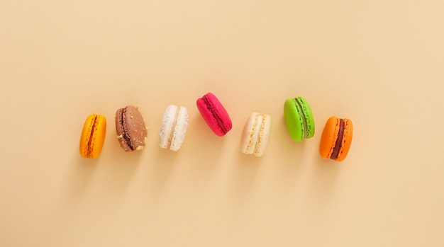 Colorful french macaroons on beige background. Almond cookies.Top view, flat lay. Valentine's day sweet gift concept,holiday, celebration.