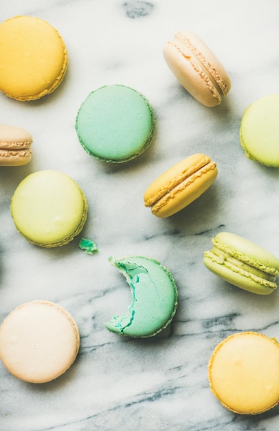 Colorful French macaroons over grey marble background vertical composition