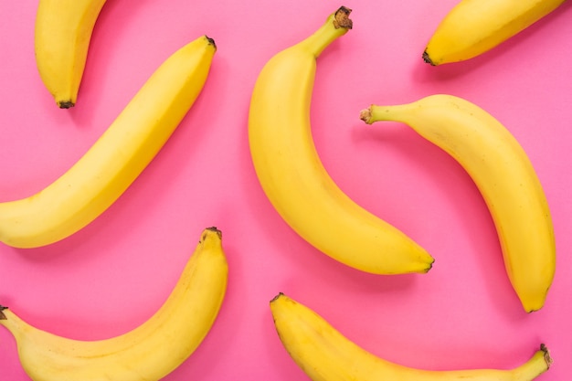 Colorful fruit pattern of fresh yellow bananas on pink surface