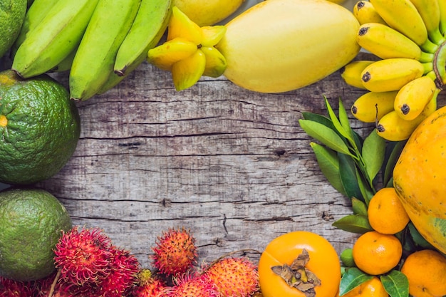 Colorful fruits on the white wooden table, Bananas, carambola, mango, papaya, mandarin, rambutan, pamela, copy space for text