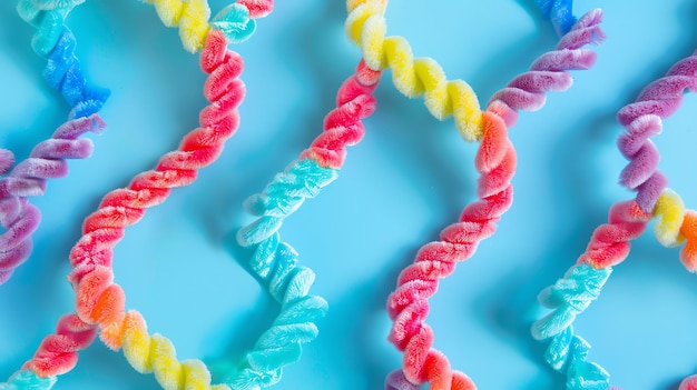 Colorful fuzzy pipe cleaners arranged in a pattern on a blue background