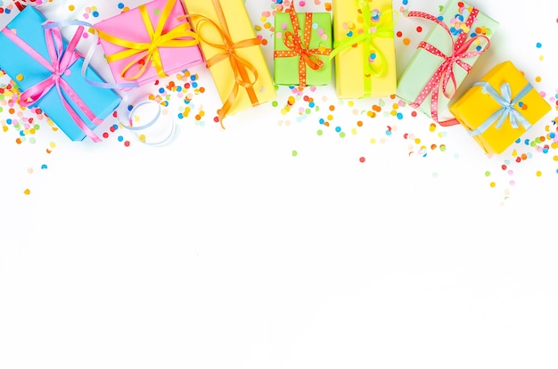 Colorful Gift boxes, paper confetti and twirled party serpentine on a white background