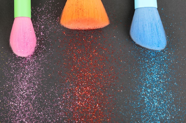 Colorful glitter crystals of eyelids makeup on black background Beauty and fashion concept Macro shot Close up Flat lay