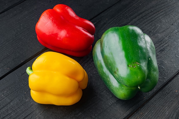 Colorful green , red and yellow peppers, on black wooden table background