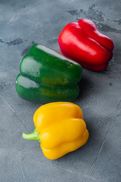 Colorful green red and yellow peppers on gray background