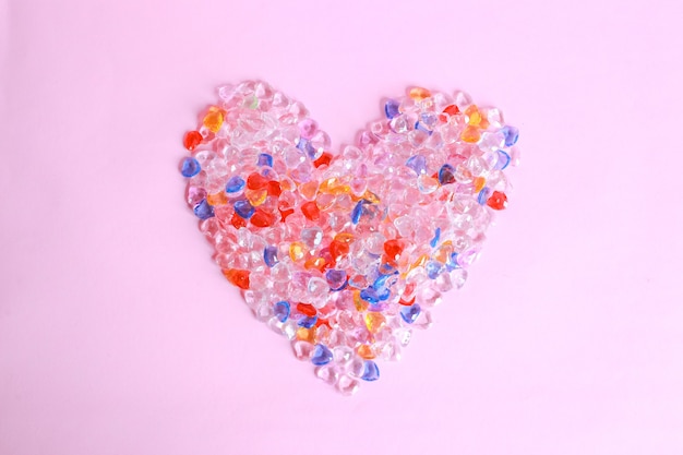 Colorful heart shape from marbles on pink background