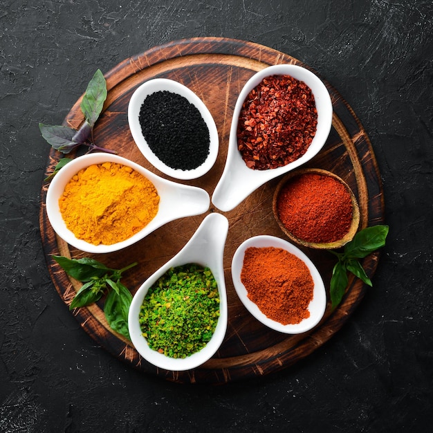 Colorful herbs and spices for cooking Indian spices On a black stone background Top view