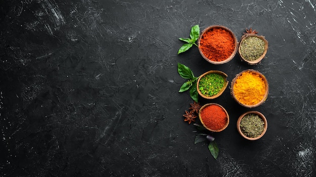 Colorful herbs and spices for cooking Indian spices On a black stone background Top view