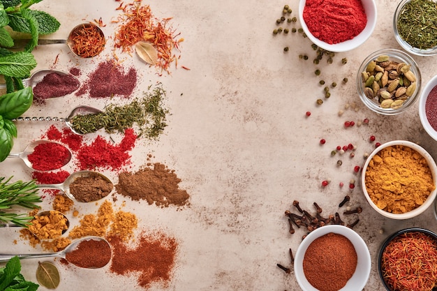 Colorful herbs and spices for cooking on light brown stone surface. Top view.