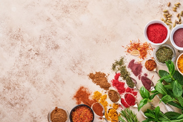 Colorful herbs and spices for cooking: turmeric, dill, paprika, cinnamon, saffron, basil and rosemary in a spoon.  