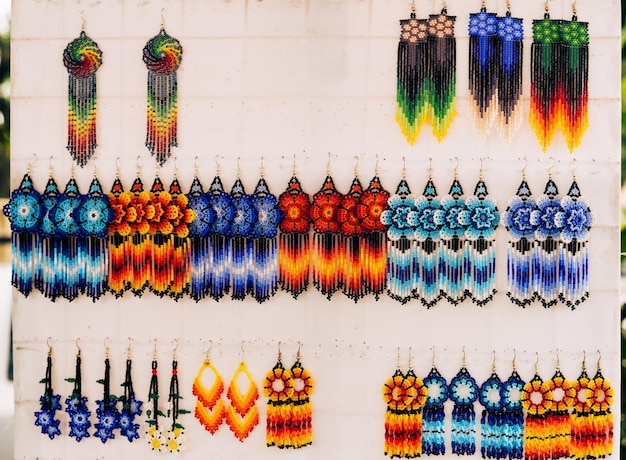 Colorful huichol earrings hanging on white display at market in Jalisco, Mexico. Mexican souvenirs