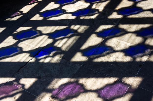 Colorful light projected on old tiles through strainedglass window