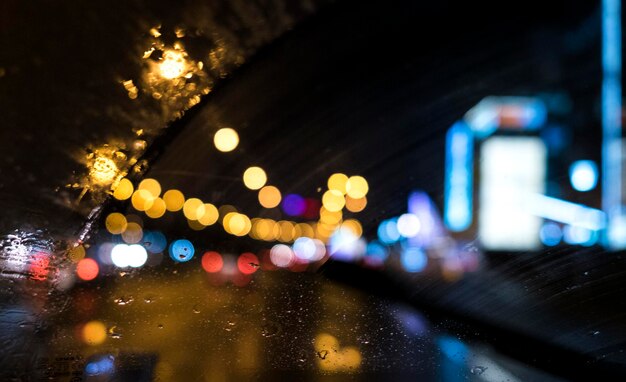 Colorful lights through a wet car window in a night city