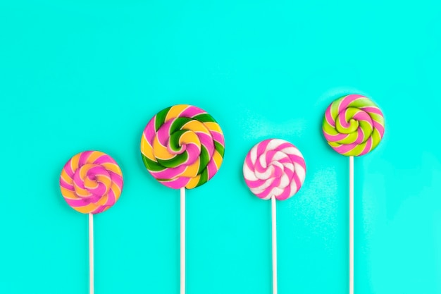 Colorful lollipops on blue, flat lay