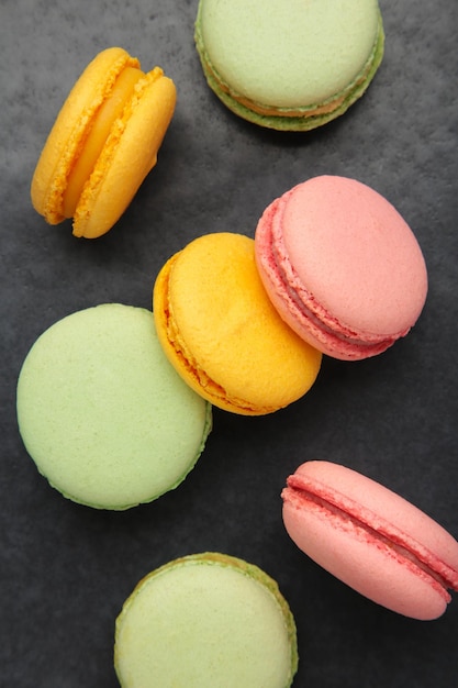 Colorful macarons cakes on dark background Small French cakes Vertical photo