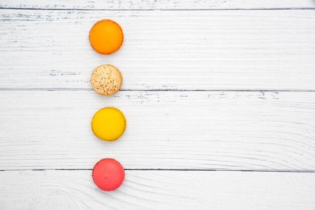 Colorful macarons on white wooden background