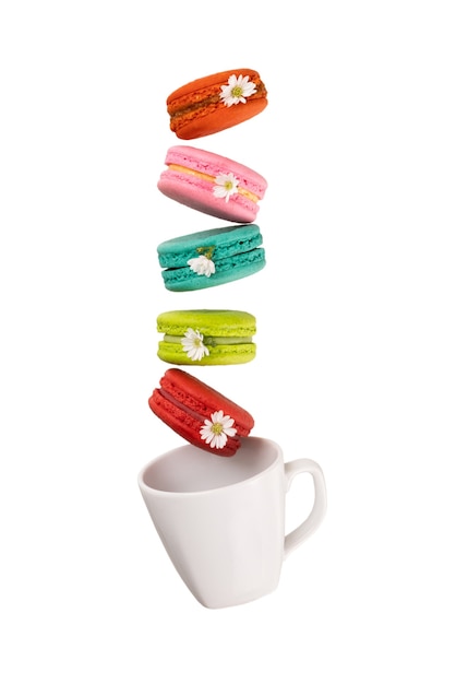 Colorful macaroons levitating on a white tea cup. Isolation on white background.