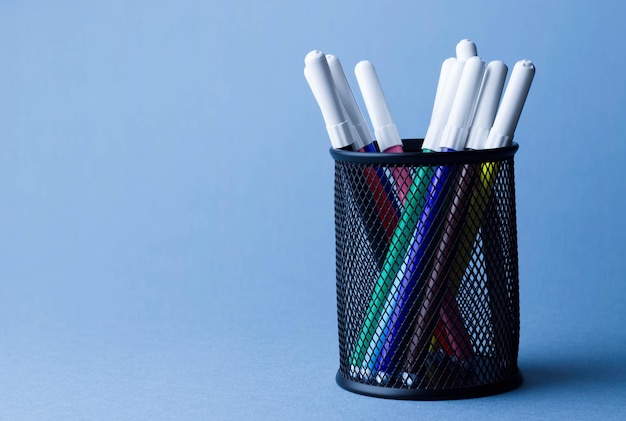 Colorful magic markers in a pencil box holder over blue background