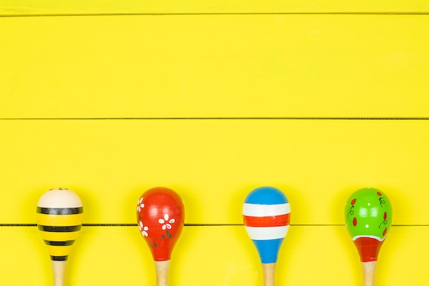 Colorful maracas  on yellow wooden board.